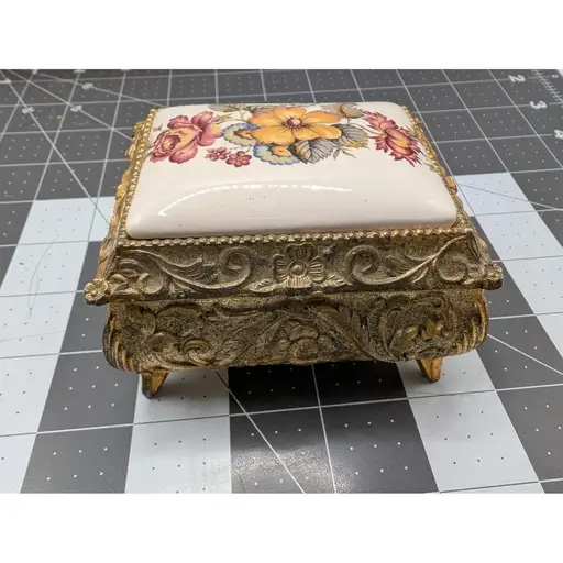 Sankyo Gold Tone Floral Porcelain Musical Jewelry Box Made in Japan vtg

14.8 oz

Vintage Sankyo musical jewelry box features a beautiful floral porcelain inlay on the lid, surrounded by an ornate gold-tone metal frame with intricate scrollwork and floral details. The box stands on four decorative feet and opens to reveal a velvet-lined compartment alongside the visible mechanical music movement protected by a clear cover. Made in Japan, this wind-up piece showcases classic craftsmanship with a textured gold-tone finish and a romantic aesthetic.

has slight wear, not org owner / unknown song, see video if platform shows it

#Floral #Cottagecore