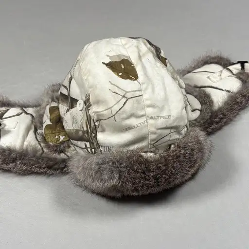 Yukon Tracks Trapper Hat S/M Realtree AP Snow Camo Genuine Rabbit Fur Ushanka

Yukon Tracks trapper hat provides exceptional warmth for cold-weather activities. This rugged headwear features a Realtree AP HD camouflage pattern on a durable shell, complemented by genuine rabbit fur trim for a soft, insulating feel. Designed with functional ear flaps that secure with a quick-release buckle, it also includes side button-up flaps for adjustable hearing. The interior is fully quilted for added comfort.

Brand: Yukon Tracks
Style: Trapper Hat
Pattern: Realtree AP HD Camo
Material: Cotton/Polyester, Rabbit Fur
Lining: Quilted Polyester
Closure: Buckle Chin Strap
Features: Ear Flaps, Side Flaps, Embroidered Logo
Color: White/Gray/Brown
Theme: Hunting, Outdoor, Winter

Keywords: Ushanka, Aviator Hat, Camo Hunting Gear, Winter Headwear, Fur Lined Hat, Cold Weather Accessories, Snow Gear, Real Tree Camouflage, Outdoor Apparel, Bomber Hat, Men's Winter Hat, Thermal Headwear, Yukon Tracks Gear, Rab